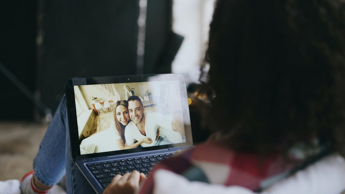 Kobieta przy laptopie prowadzi wideorozmowę z uśmiechniętą parą widoczną na ekranie